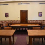 U.S. Export Controls Trigger Worldwide AI Model Shutdown Empty courtroom with wooden tables, chairs, and a door.