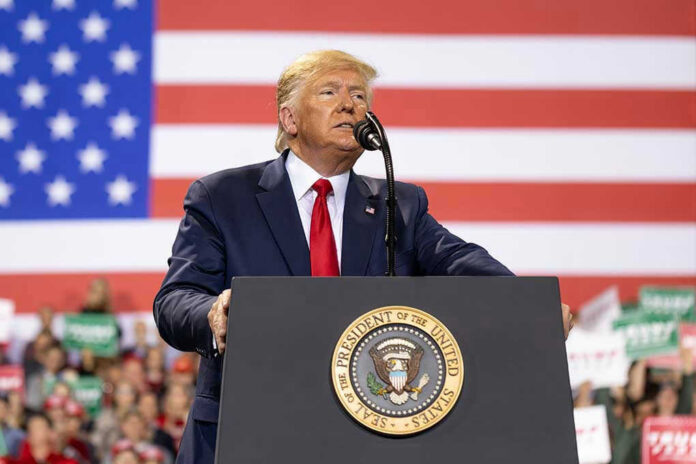 1677446164-1 Man speaks at podium with U.S. flag background.