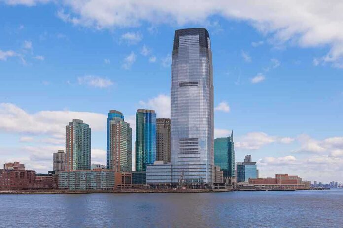shutterstock_122104555 A modern city skyline featuring tall buildings along a waterfront under a cloudy sky