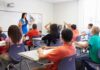Teacher Fired After Student Kiss Skit Controversy Teacher in a blue dress instructing students in a classroom with hands raised