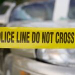 Gunfire Erupts Near Toledo Festival, 12 Shot Yellow police tape reading POLICE LINE DO NOT CROSS in front of a vehicle