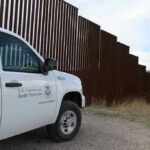Court Records and Family Claims Raise Border protection vehicle near a large metal fence.