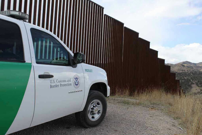 1478048393 Border protection vehicle near a large metal fence.