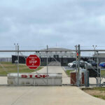 Chain-link fence with Restricted Area Stop No Photography sign.