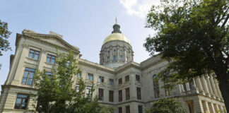 Historic building with a gold dome and surrounding trees.