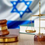 Gavel and scales of justice with Israeli flag in background