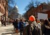 Rhode Island Lawmaker Faces Backlash Over ICE Threat Crowd of protesters walking toward a domed capitol building