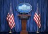 White House press podium with microphones and two American flags