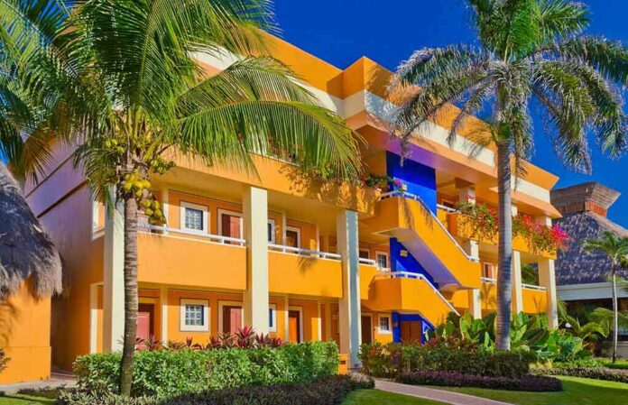 shutterstock_140180596 Colorful resort building surrounded by palm trees and lush greenery