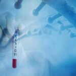 Gloved hand holding a COVID-19 test tube beside a stylized DNA helix