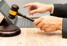 Judge's gavel held over block near laptop on wooden desk