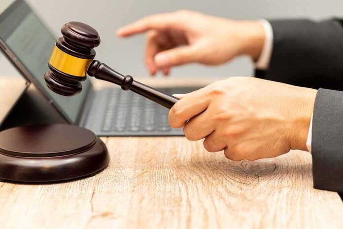 Judge's gavel held over block near laptop on wooden desk
