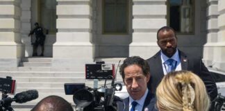 Man in suit speaks to reporters outside a government building