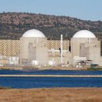 Missiles Strike Near Iran’s Only Nuclear Plant Nuclear power plant with domed structures beside a water body and mountains in the background