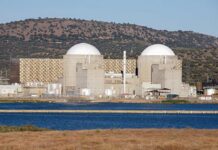 Missiles Strike Near Iran’s Only Nuclear Plant Nuclear power plant with domed structures beside a water body and mountains in the background