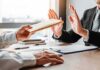 Businessperson refusing an envelope at a desk