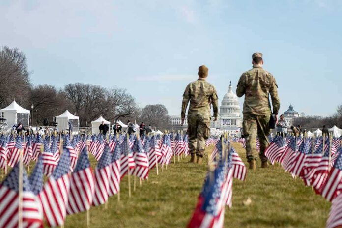 Two soldiers walk among American flags toward the U.S. Capitol