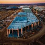 aerial view of large industrial building under construction at sunset