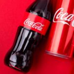 Coca-Cola bottle and cans on a red background