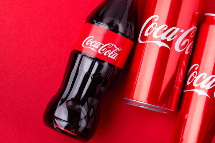 shutterstock_1939159003 Coca-Cola bottle and cans on a red background