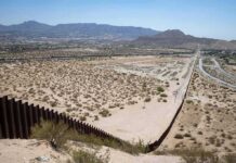 Border Wall Threatens 6,000-Year Treasures Border fence cutting across a desert landscape with mountains in the distance