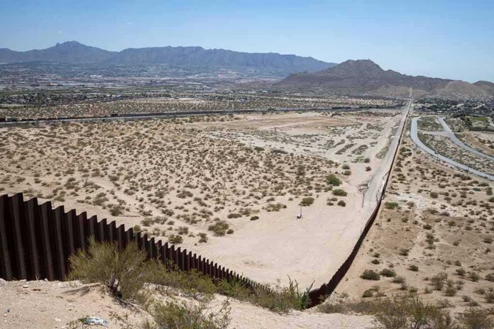 shutterstock_2006817503 Border fence cutting across a desert landscape with mountains in the distance