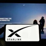 Smartphone showing Starlink logo in front of a computer screen