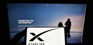 Smartphone showing Starlink logo in front of a computer screen