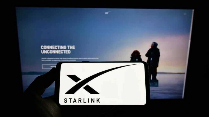 shutterstock_2097402760 Smartphone showing Starlink logo in front of a computer screen