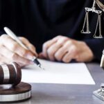 Hollywood’s $110B Deal Stopped Judge writing at desk with gavel and Lady Justice statue