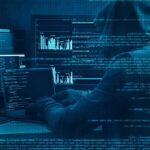 FBI Alarm: AI Is Supercharging Online Scams Hooded person at multiple computer screens with code and charts