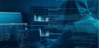 Hooded person at multiple computer screens with code and charts