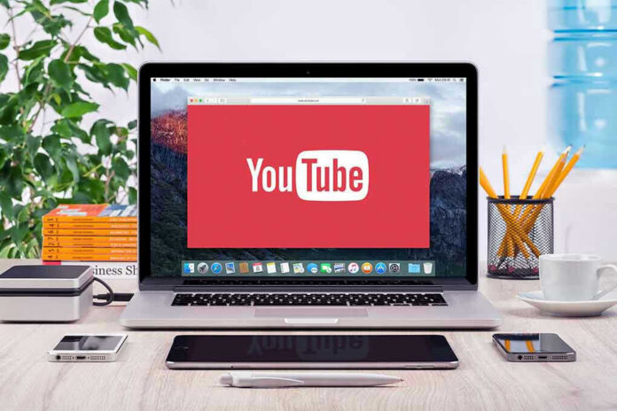YouTube logo on a laptop screen on desk.