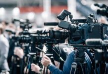 “JD 48” Chants Fuel 2028 Buzz Broadcast cameras on tripods at a press event