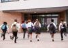 Students in uniforms running toward a school entrance