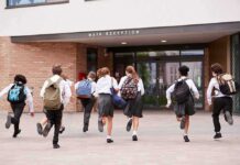 Students in uniforms running toward a school entrance