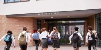 Students in uniforms running toward a school entrance