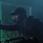 Green ‘Lanterns’ Sparks Culture Clash man with headset gestures while working at a control station