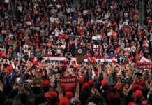 Trump Offers: $1 Trillion Tease Speaker at podium addressing large crowd in arena