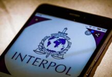 WANTED: FSB Issued International Arrest Warrant to Telegram Founder Smartphone screen displaying Interpol logo and text