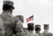 From Deadly Ambush to Airstrikes: U.S.-Iran Tensions American flag above blurred soldiers in formation