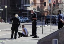 Teen Dead: Fake Pills, Deadly New Threat Police officers detain a seated man on a city sidewalk