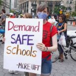 Union Endorsement: NYC Teachers Faces Power Struggle Protester holding a sign at a city street demonstration