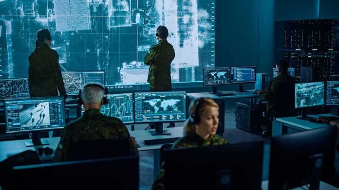 Military analysts monitor data on multiple screens in a command center
