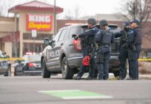 Austin Shooting Under Investigation Police officers gather beside a patrol SUV at a taped-off scene