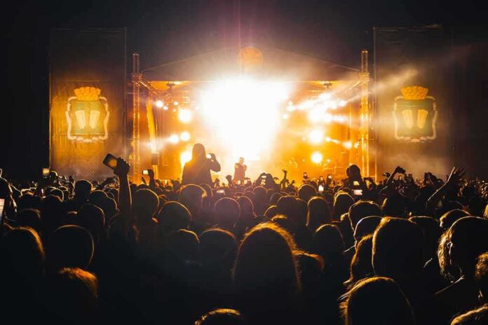 shutterstock_1971943841 Crowd at a nighttime concert with bright stage lights