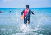 Teen Lifeguard Who Saved Boy Honored by Baywatch lifeguard wading into ocean with rescue buoy