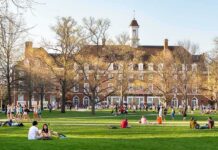 Viral Clip Fallout: College Exit Shocks Campus Students relaxing on a campus quad in front of a brick academic building