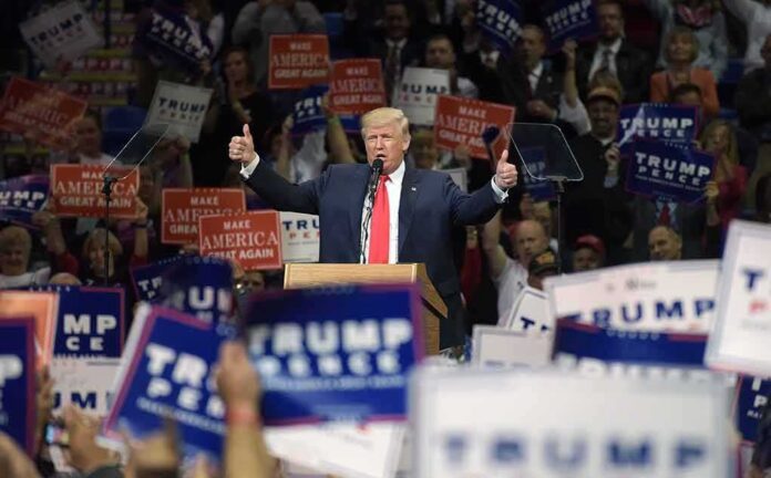 shutterstock_1427778638 Donald Trump speaks at a rally, giving two thumbs up
