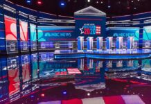 Lawsuit Challenges $20M in Border Funds for Ads Televised debate stage with multiple podiums and bright red, white, and blue lighting